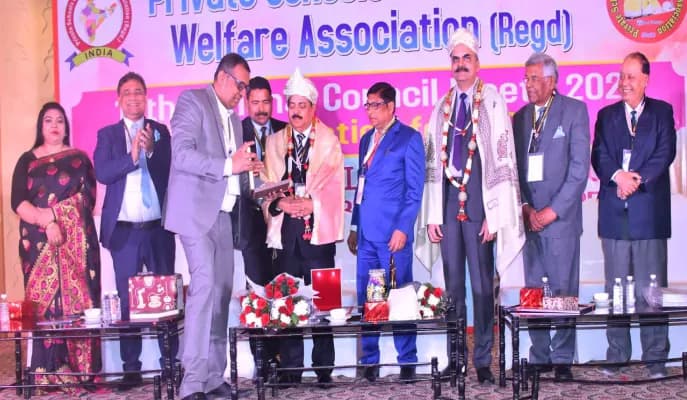 Guests in suits and shawls on stage at a National Council Meet of the association