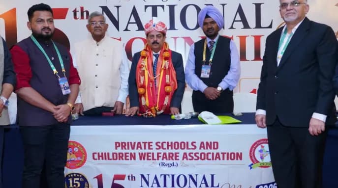 A guest wearing a turban and shawl stands with delegates behind the 15th National Council Meet table